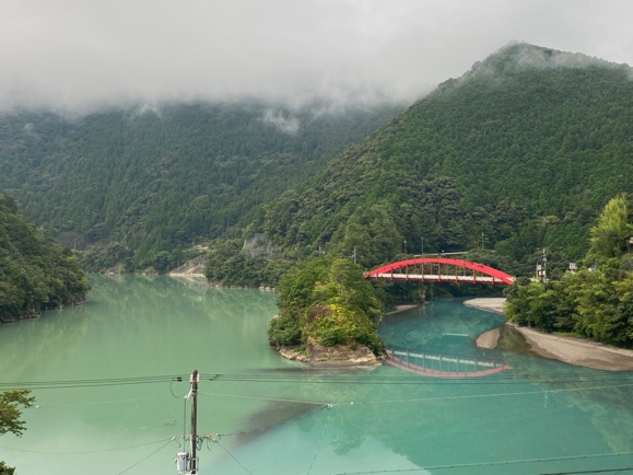 <font color='blue' size='2'>十津川温泉街。鮮やかな赤い橋の先で2色の緑色の水が合流している。感動的!!あまりの美しさに言葉が出てこない。この景色を見にまた行きたい!!</font>